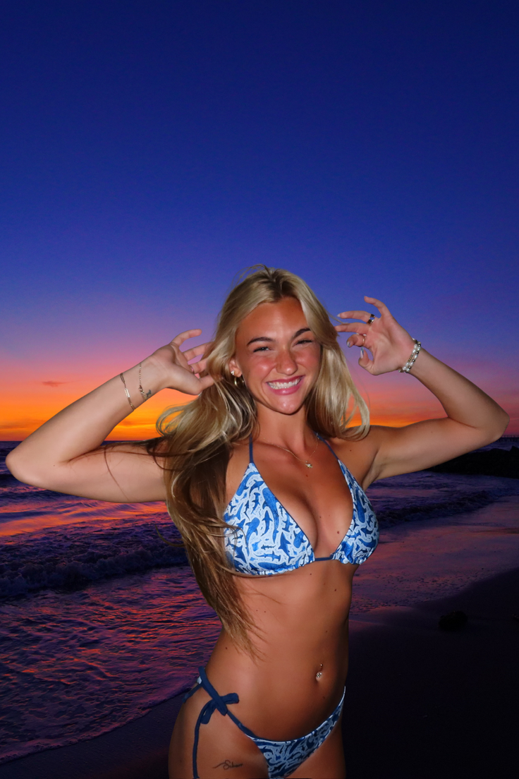 Woman in a blue bikini on a beach at sunset