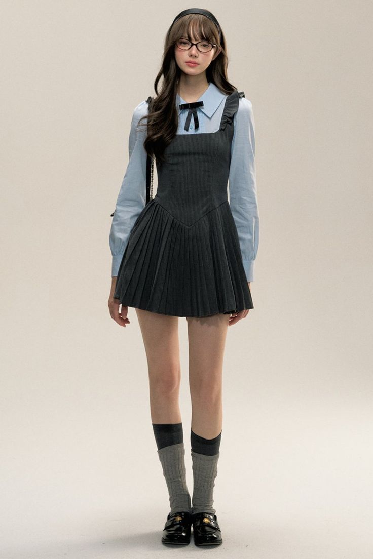 Woman in a pleated dress over a blue shirt, glasses, and a headband