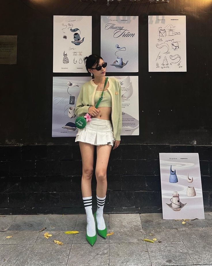 Woman in a white pleated skirt and green crop top with a cardigan, posing outdoors