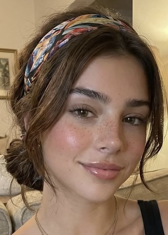 Woman with brown hair, a colorful headband, and freckles smiling at the camera