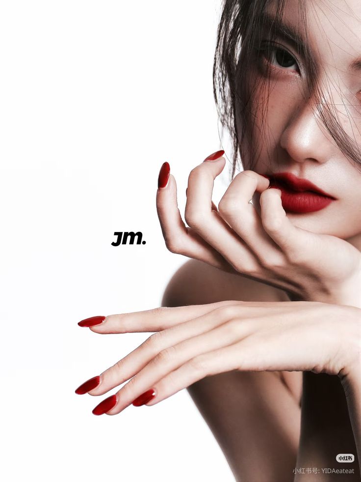 Close up of a woman with red lipstick and nails, hair partially covering her face