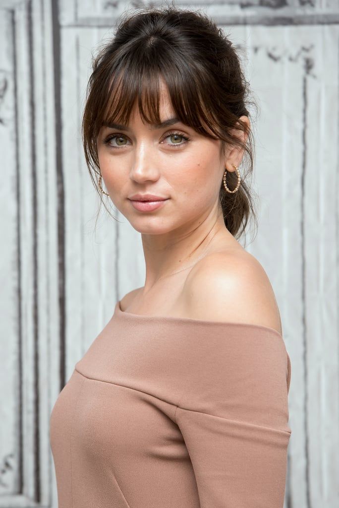 Woman with brown hair and green eyes wearing an off-shoulder top