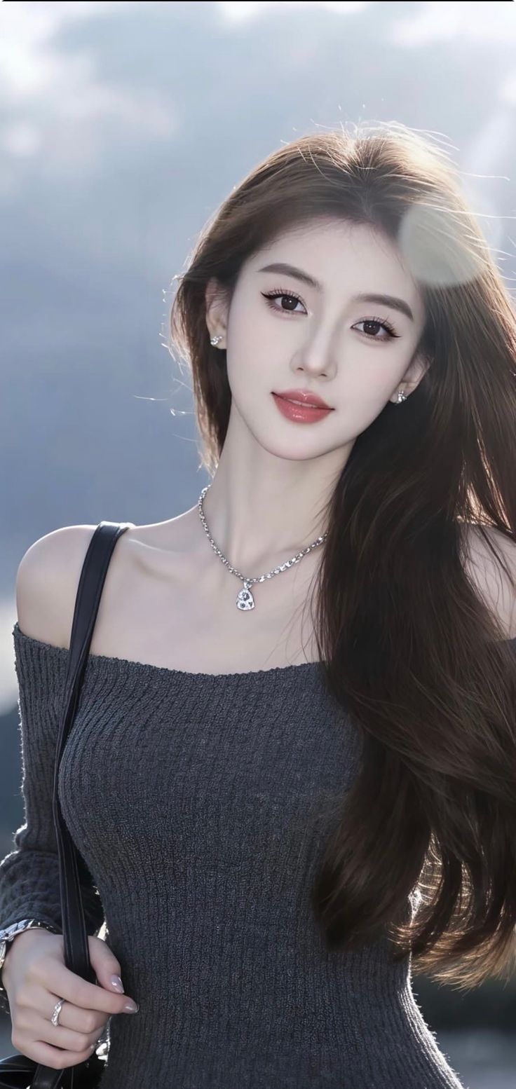 Woman with long brown hair wearing an off-shoulder top and necklace outdoors