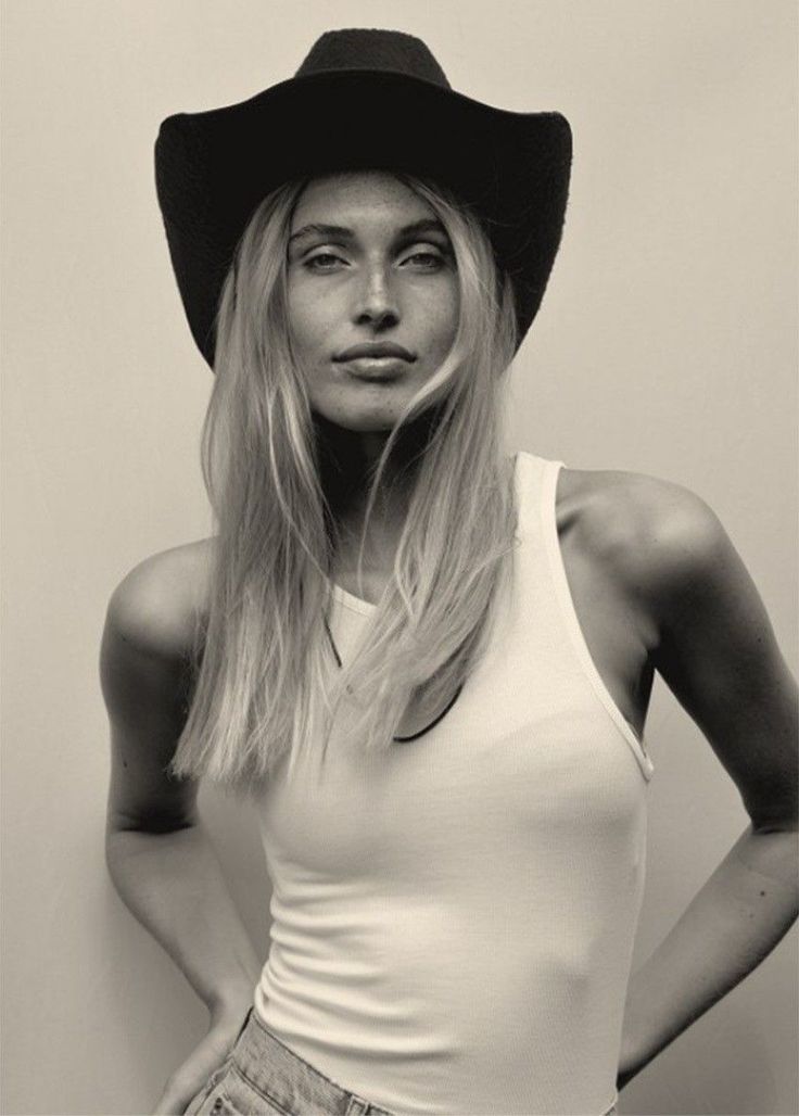 Woman in a cowboy hat and white tank top with long blonde hair