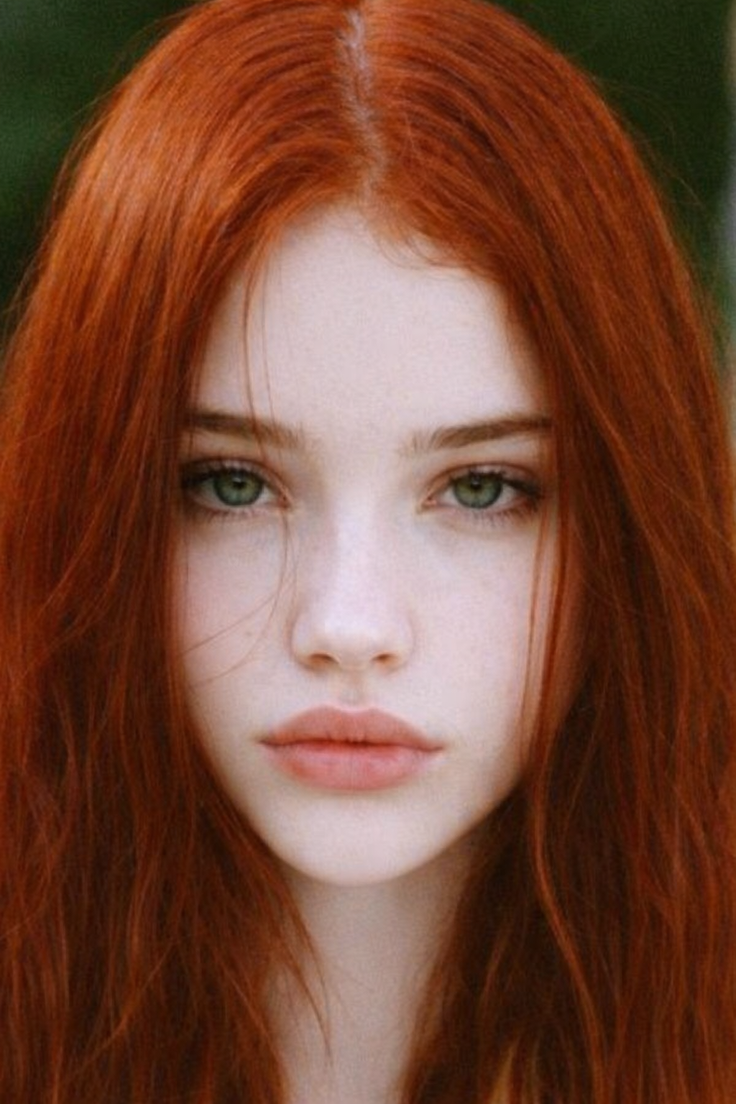 Close up portrait of a woman with long red hair and green eyes