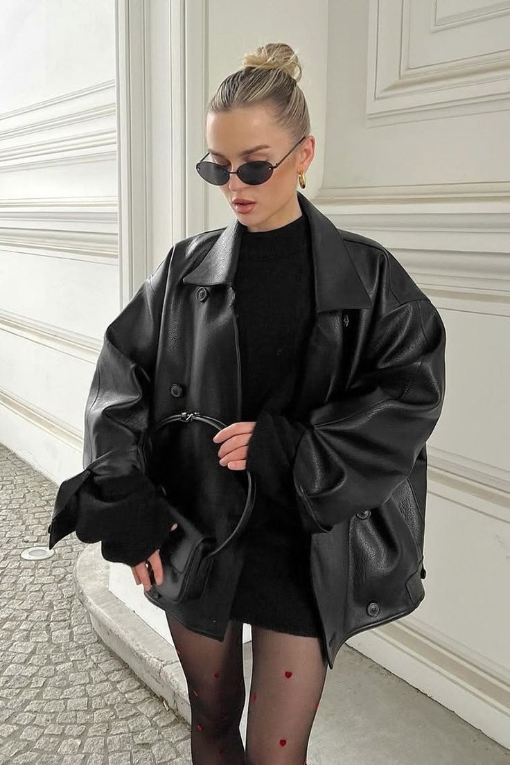 Woman in a black leather jacket and heart pattern tights holding a handbag