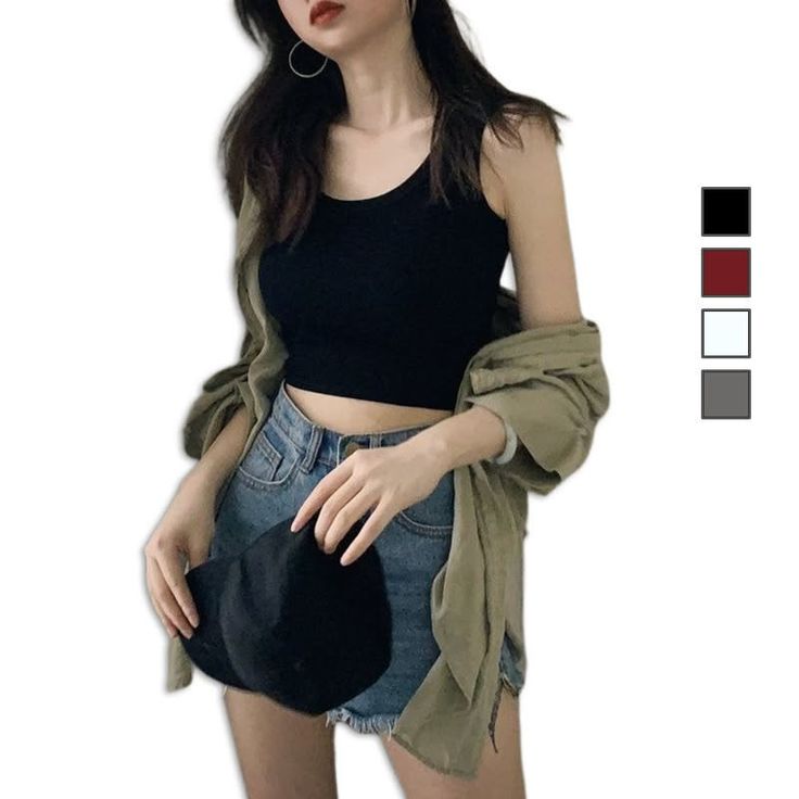 Woman in a black crop top and denim shorts with a shirt draped over her arms