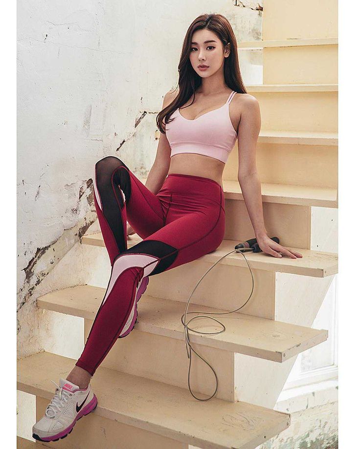 Woman in a pink sports bra and red leggings sitting on stairs with a jump rope