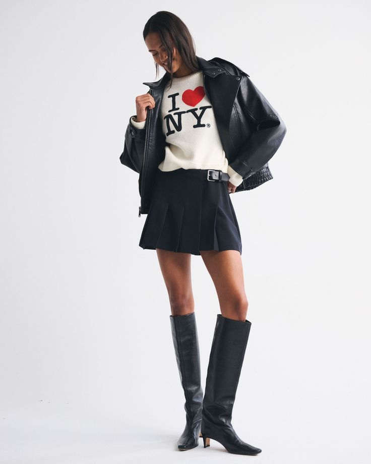 Woman in a black leather jacket and pleated skirt with knee-high boots