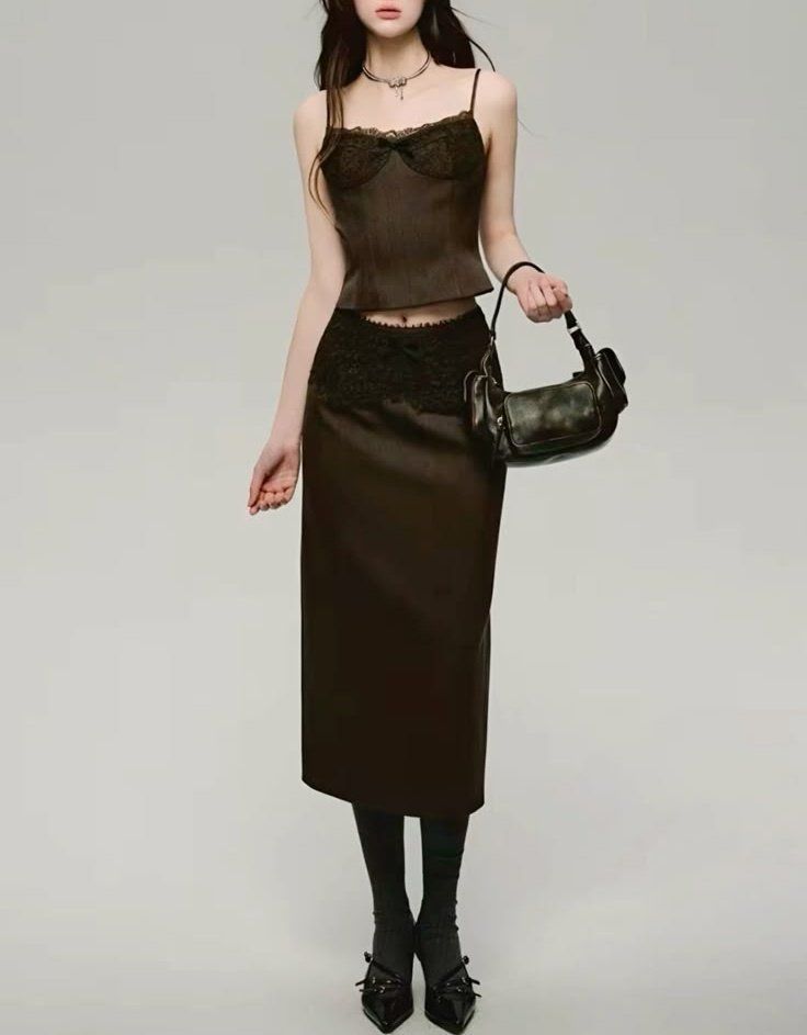Woman in a dark lace camisole and midi skirt with a shoulder bag