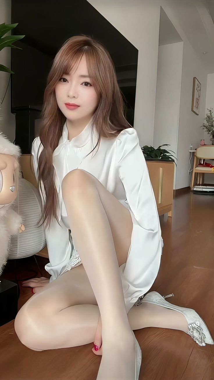 Woman in a white dress and pantyhose sitting on a wooden floor