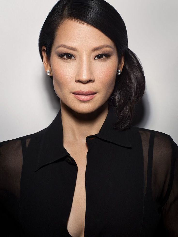 Woman with black hair and diamond earrings wearing a sheer black top