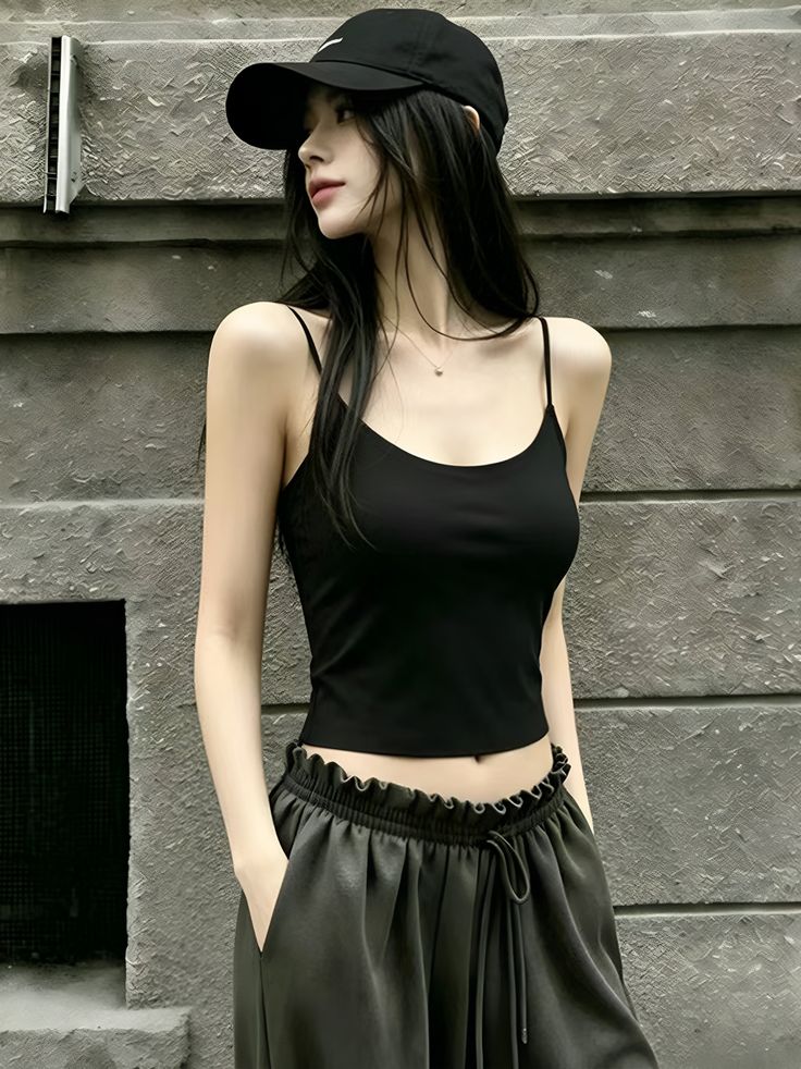 Woman with long black hair wearing a black tank top and baseball cap outdoors