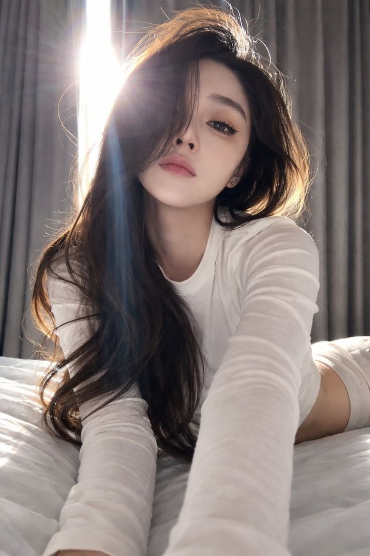 Woman with long hair in a white top lying on a bed with backlight