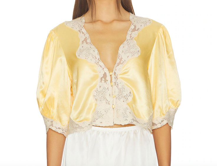 Woman wearing a yellow satin and lace cropped top with puffy sleeves