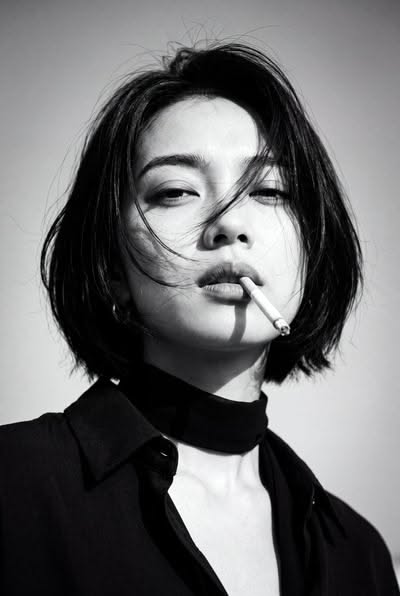 Woman with short hair and a choker, holding a cigarette in her mouth