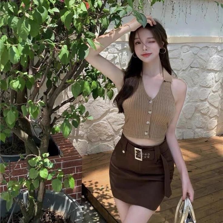 Woman in a brown halter top and mini skirt winking outdoors
