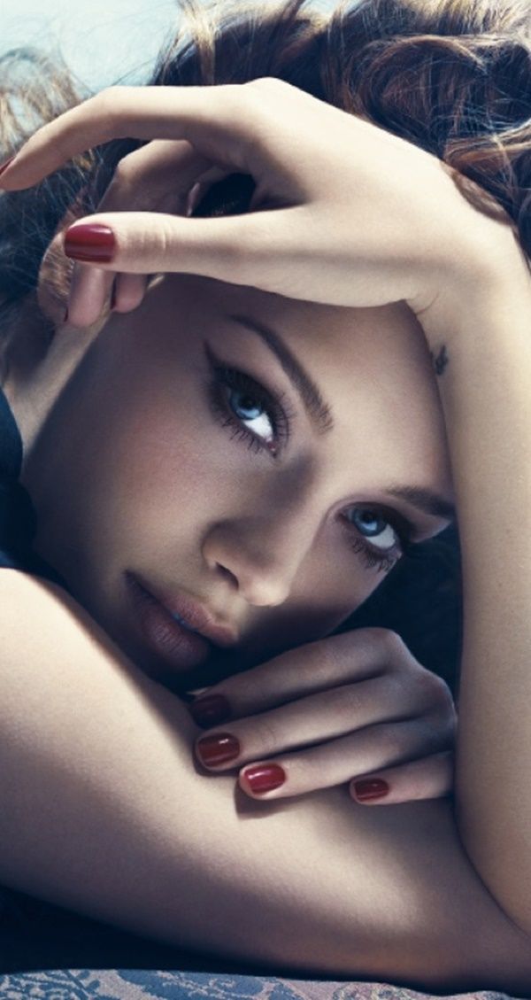 Close up portrait of a woman with blue eyes and red nails