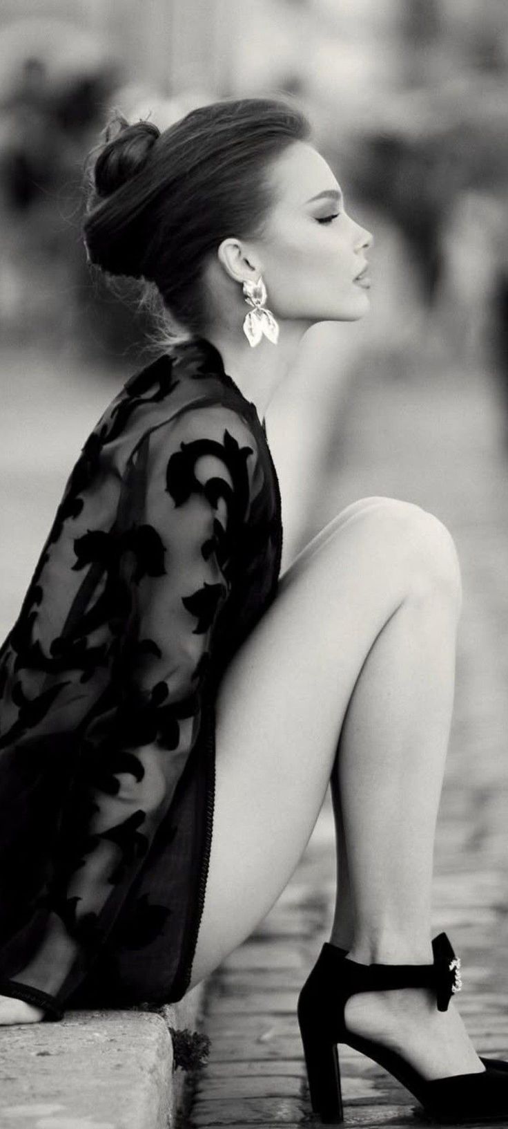 Woman in a sheer top and high heels with an updo, in black and white