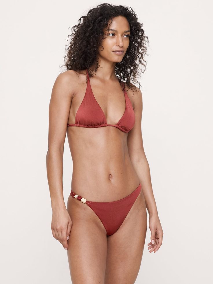 Woman with curly hair wearing a rust-colored bikini in a studio shot