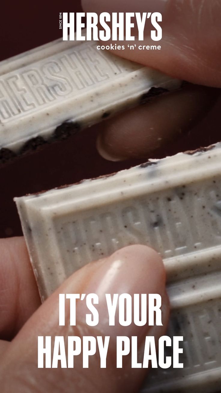Hands holding a Hershey's Cookies 'n' Creme chocolate bar