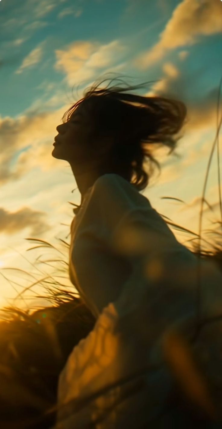 Woman with long hair in motion against a golden hour sky