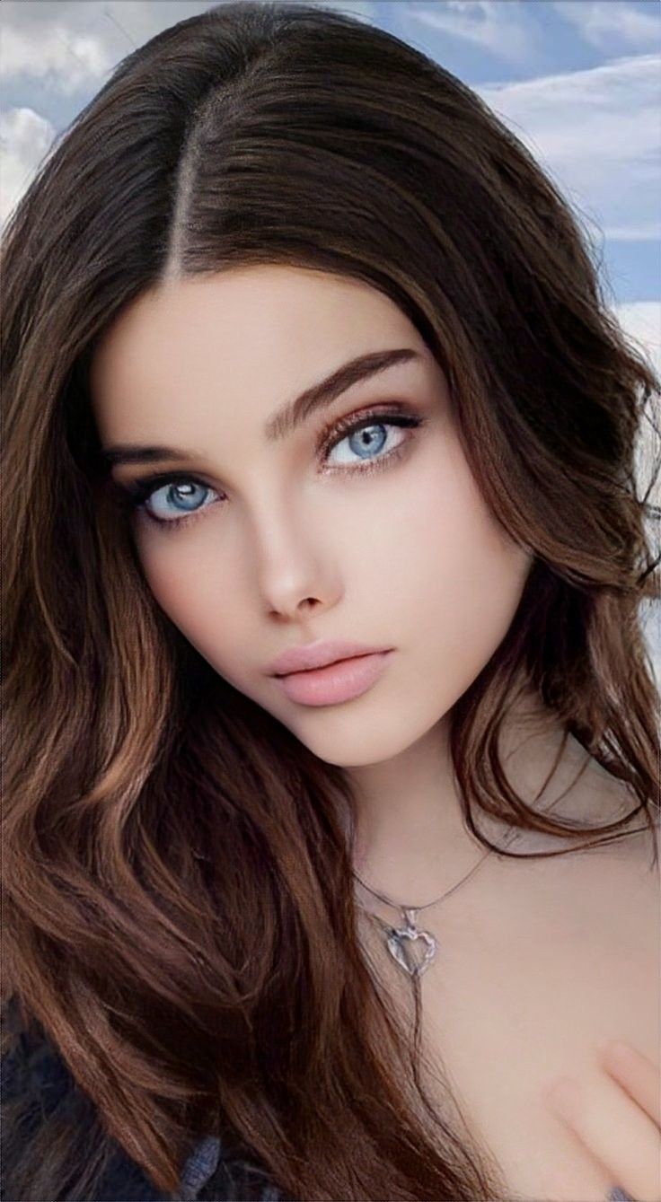 Woman with long brown hair and blue eyes wearing a heart necklace