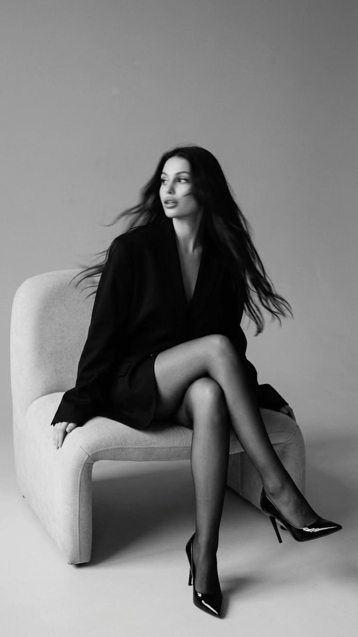 Woman in a black blazer and pantyhose sitting in a studio