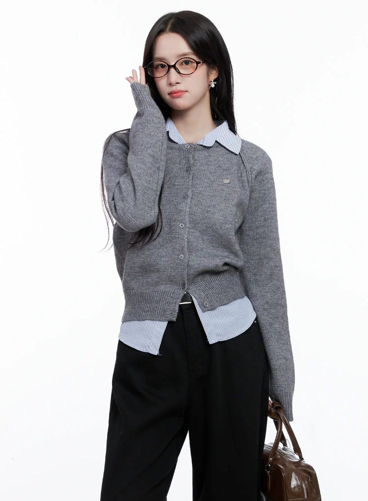 Woman in a gray cardigan and striped shirt holding glasses