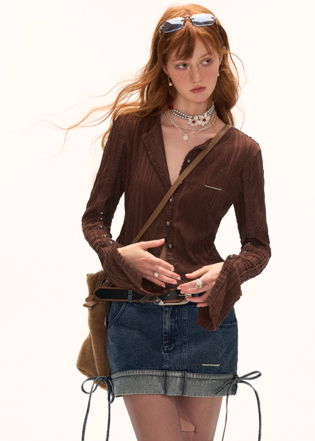 Woman with red hair wearing a brown top and denim skirt against a white background