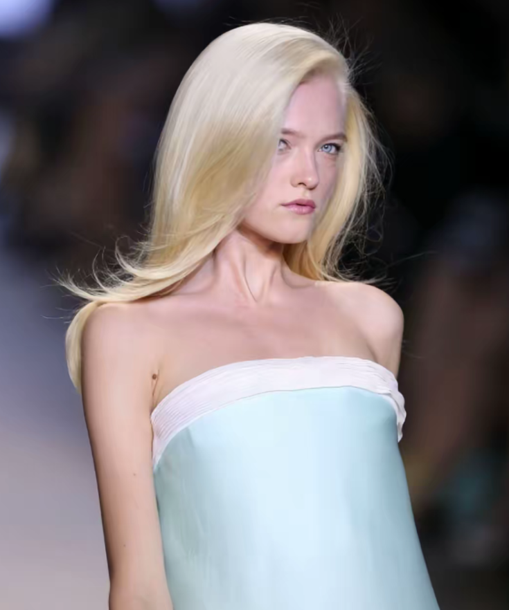 Woman with long blonde hair and blue eyes wearing a strapless dress