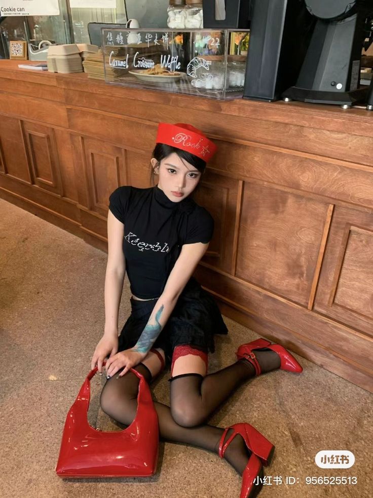 Woman in a red hat and black outfit with red accessories posing indoors