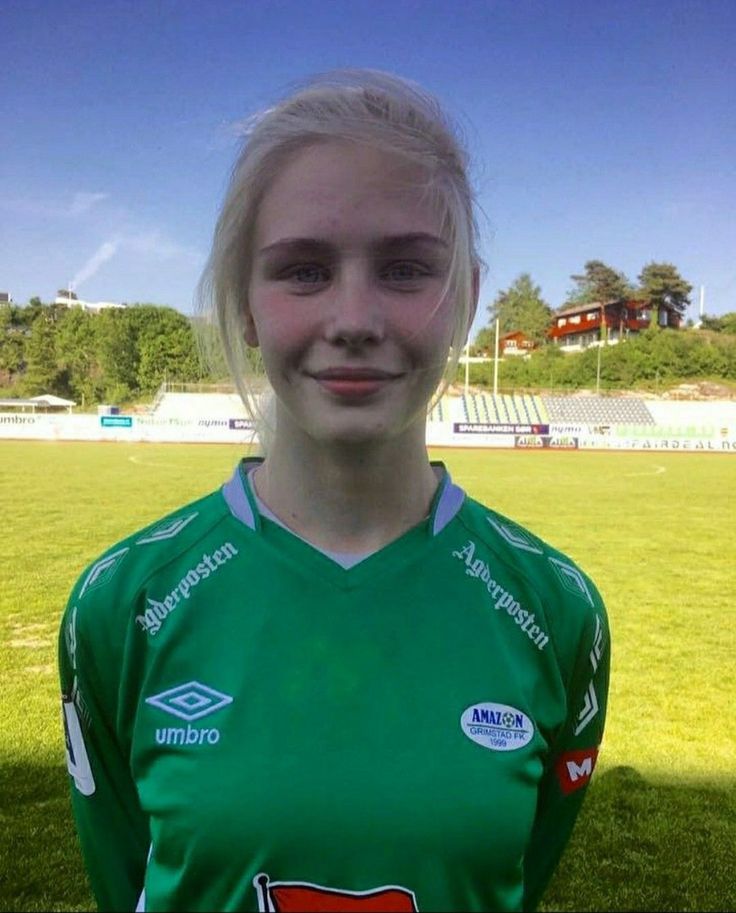 Young woman in a green soccer jersey on a sunny outdoor field