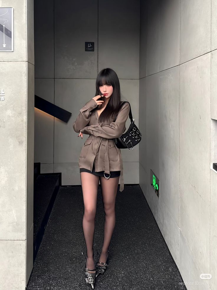 Woman with long black hair wearing an oversized shirt and black shorts indoors