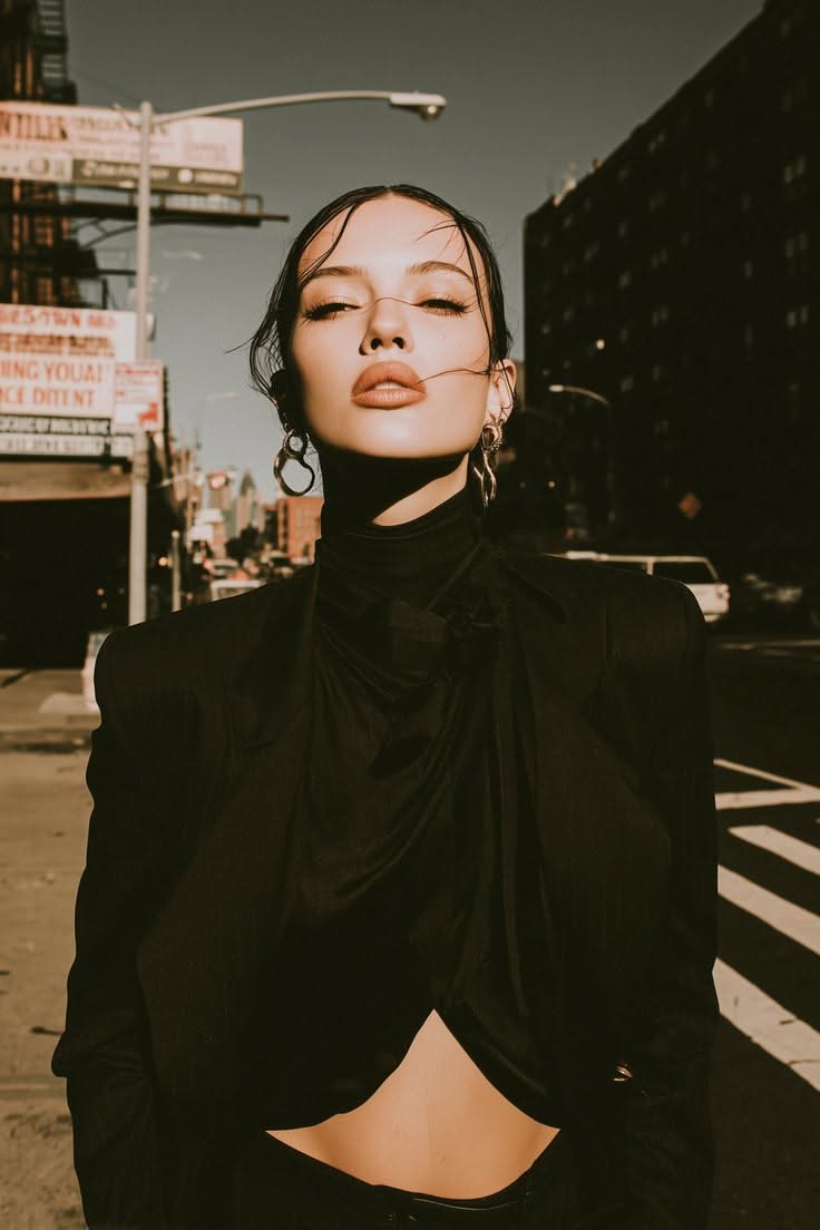 Woman in a black outfit with exposed midriff on a street with dramatic lighting