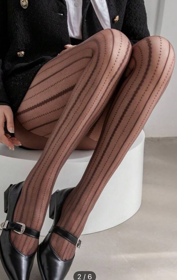 Person wearing patterned tights, a black blazer, and mary jane shoes
