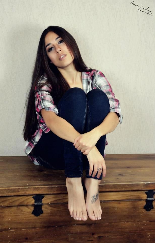 Woman with long hair wearing a plaid shirt and jeans, sitting on a wooden chest