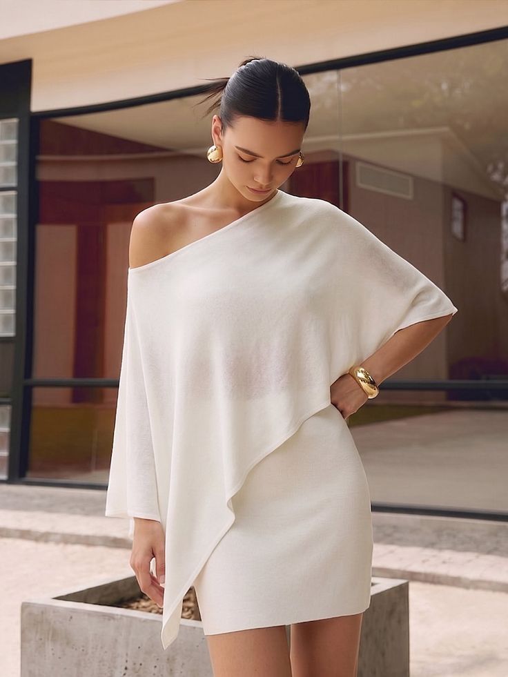 Woman in a white off-shoulder dress with gold jewelry outdoors