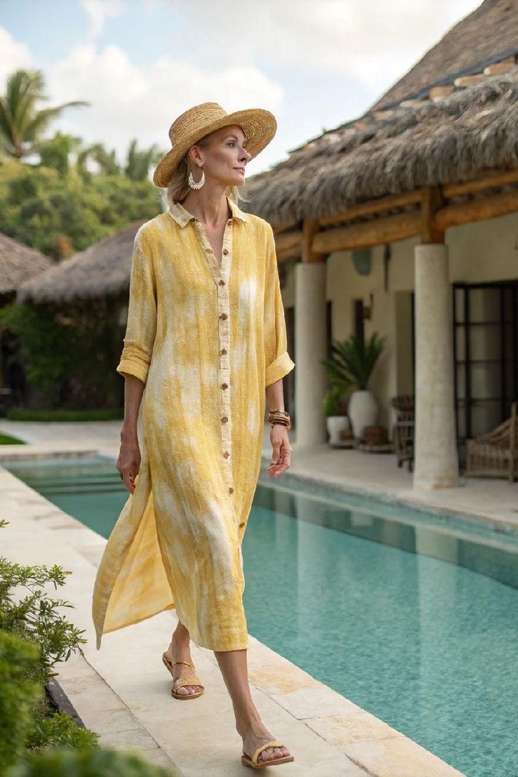 Woman in a yellow dress and straw hat walking by a pool