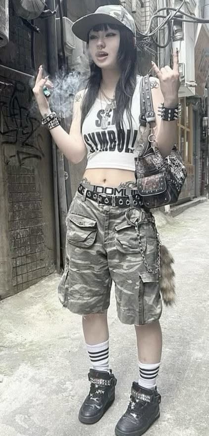 Person in a camo hat and cargo shorts with a crop top in an alleyway