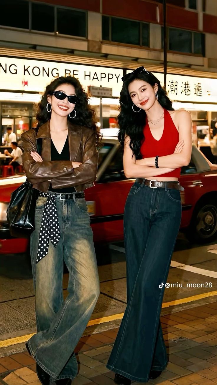 Two women posing on a street at night, one in a leather jacket and the other in a red top