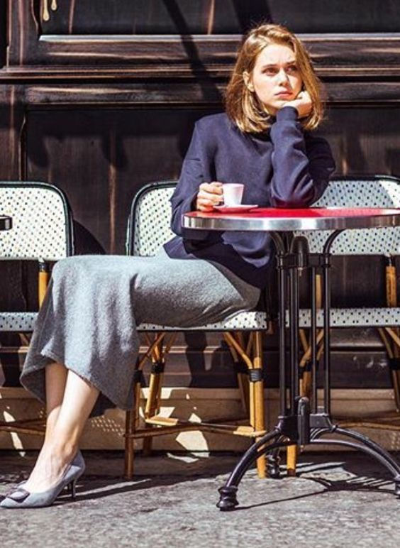 Woman with short hair sitting at an outdoor cafe table with a coffee cup