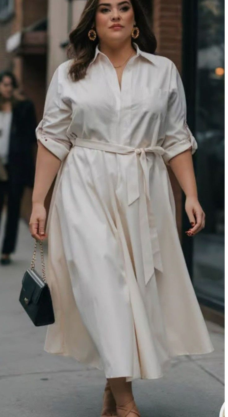 Woman in a white dress with a belt and handbag walking on a street