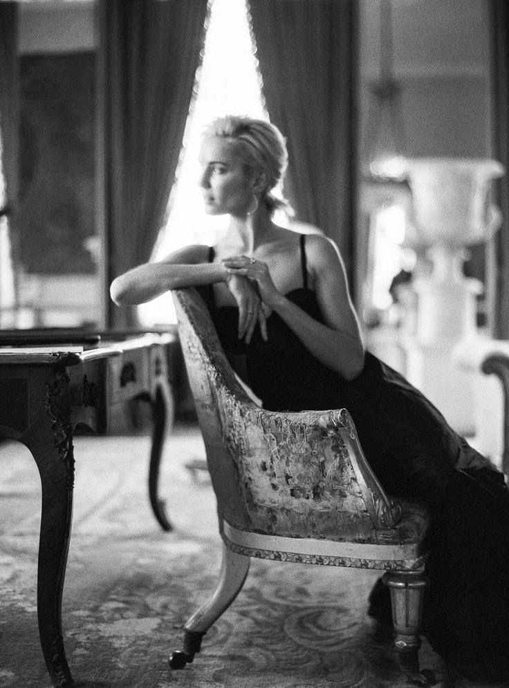 Woman in an elegant dress sitting in a chair with backlight from a window