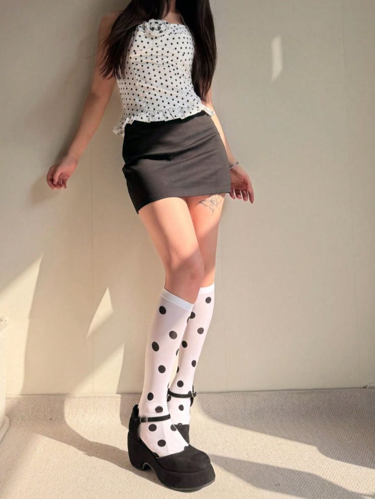 Woman in a polka dot top and mini skirt with knee-high socks and platform shoes