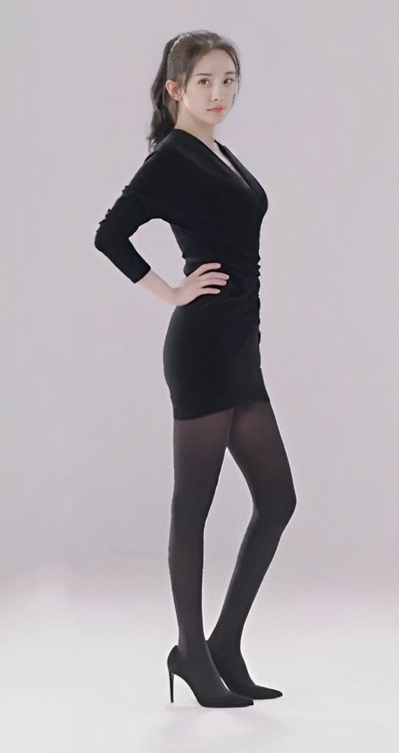 Woman in a black dress and tights posing in a studio