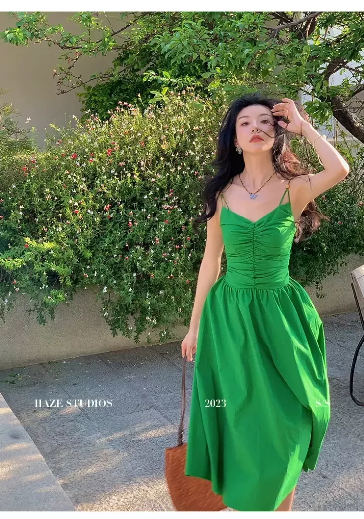 Woman in a green dress standing outdoors in a garden setting