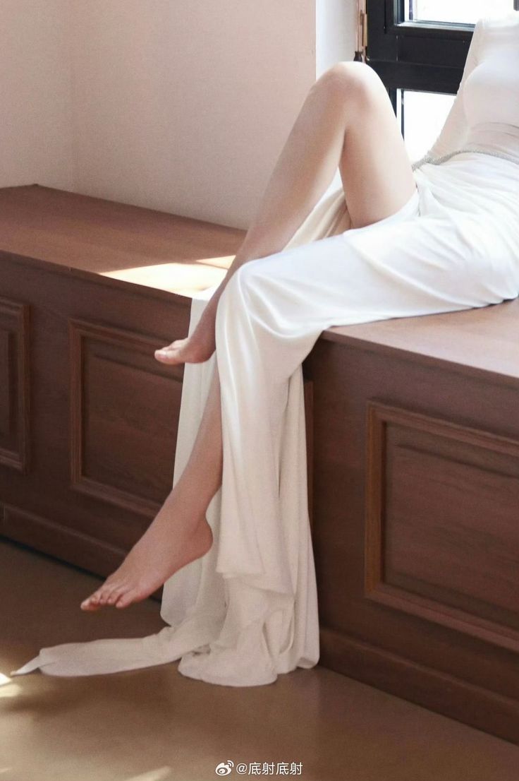 Woman in a white dress with exposed legs and bare feet indoors