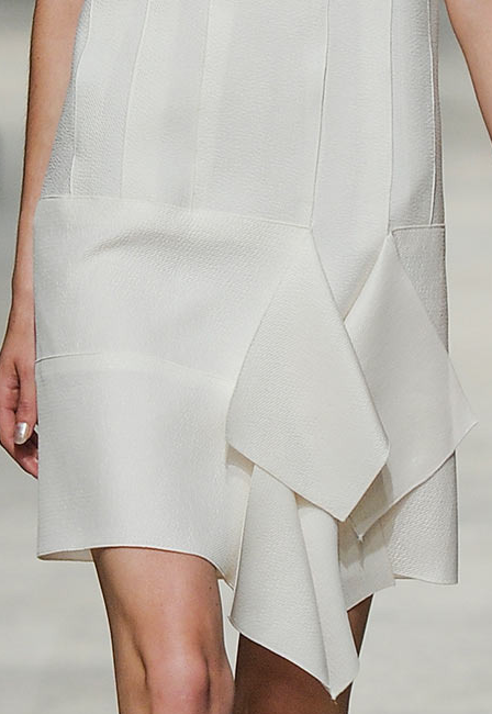 Close up of a white dress with a ruffled skirt and textured fabric
