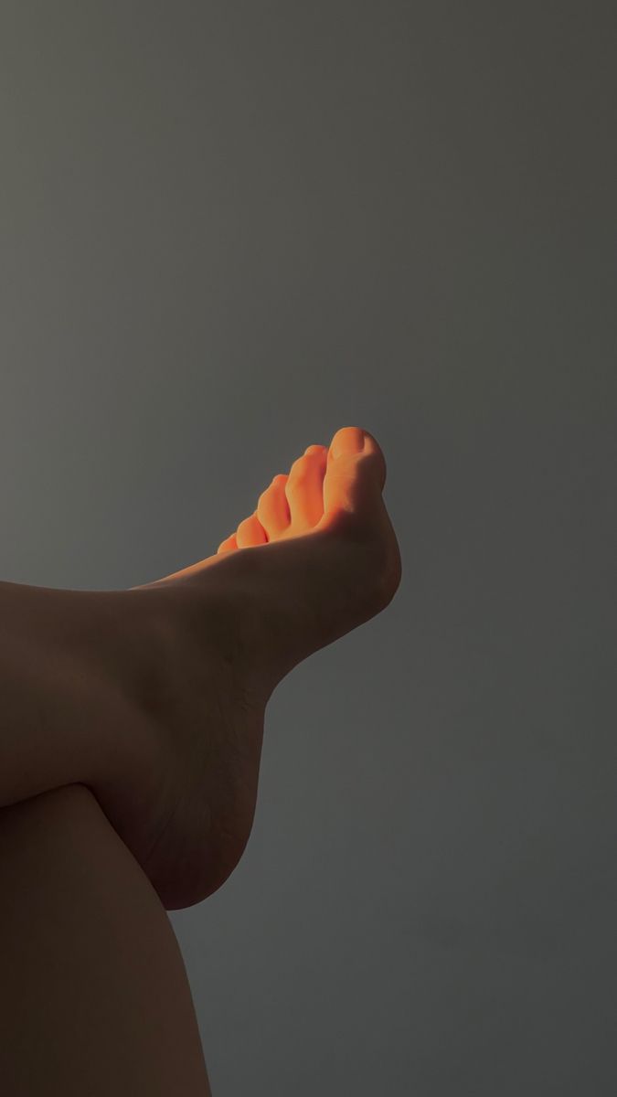 A foot illuminated by golden hour light against a dark background